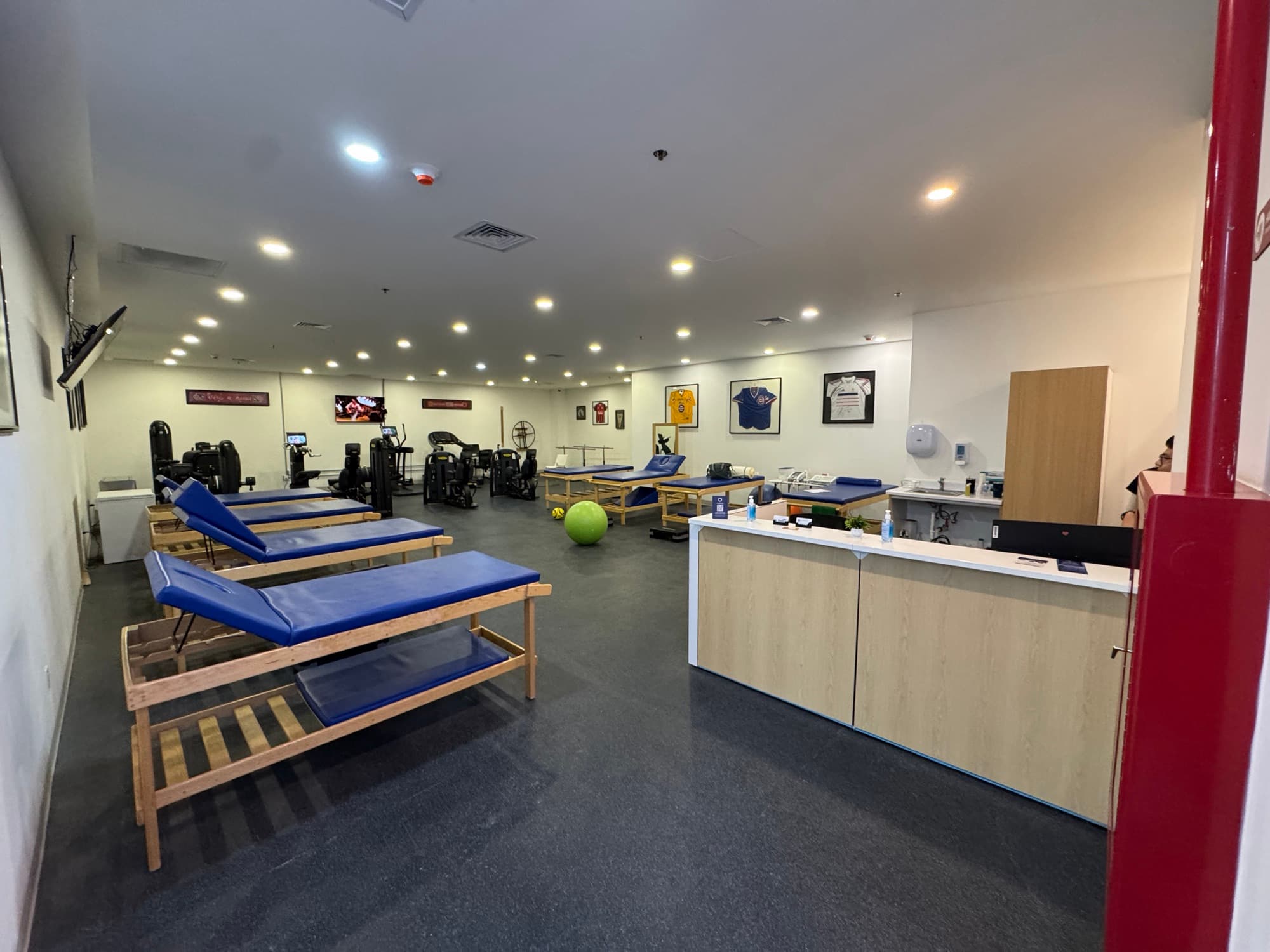 Physical rehabilitation gym with padded treatment tables, exercise equipment and a reception counter