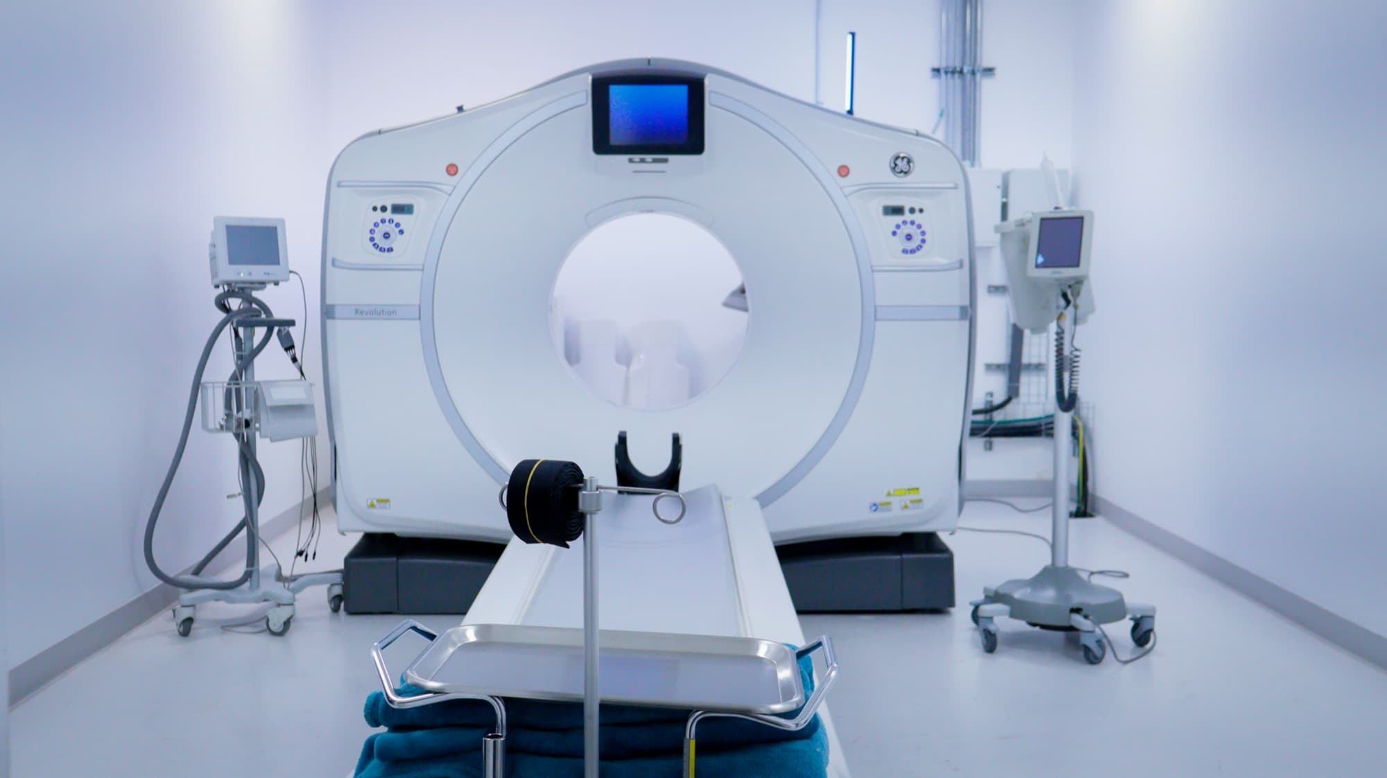 CT scanner with its patient table extended in an empty scan room