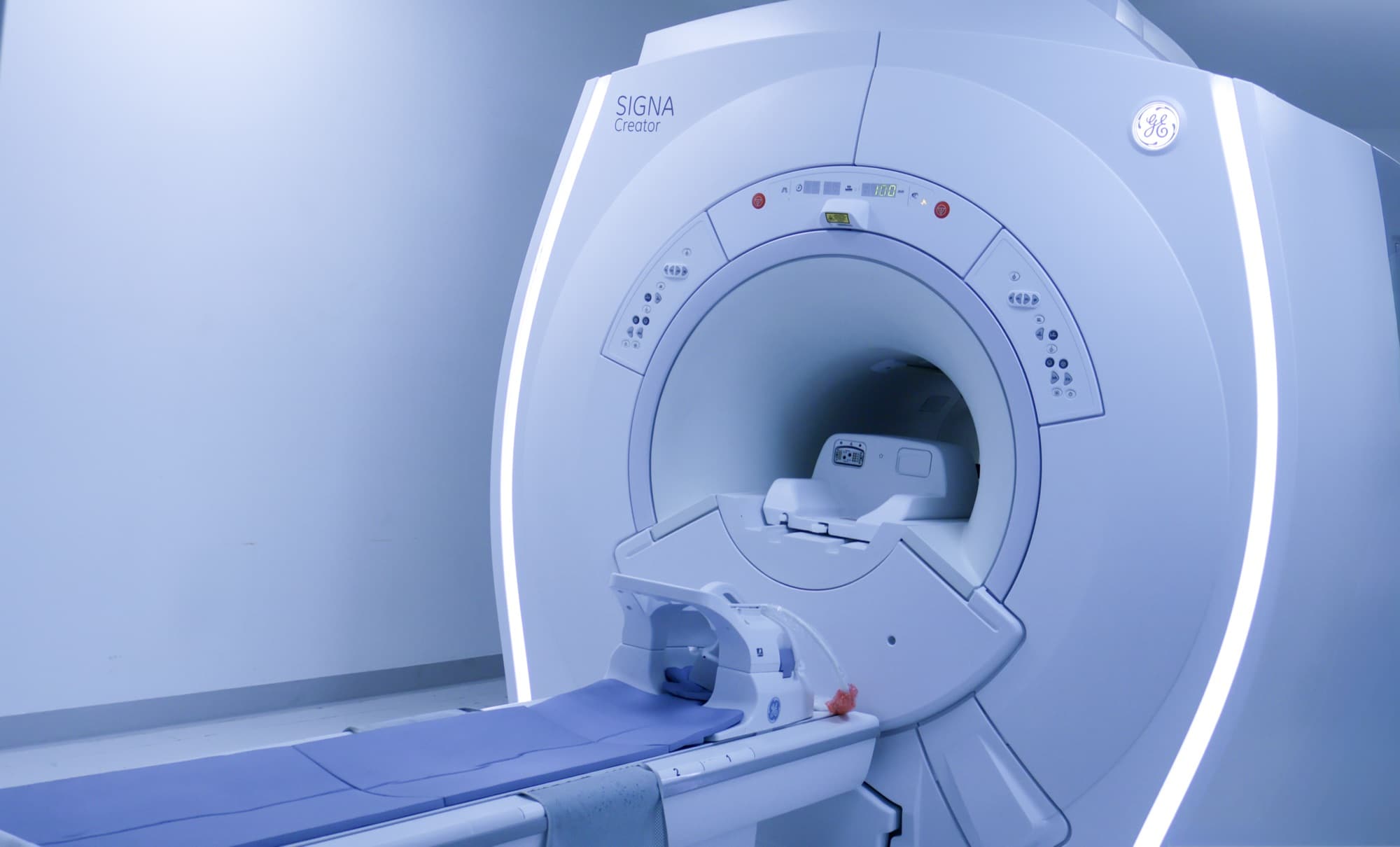 MRI scanner seen from an angle with the table extended and a head coil mounted